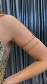 Brazalete dorado de metal con doble aro y terminaciones esféricas.