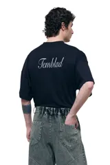 Remera negra de corte oversize con cuello redondo y estampado de león con efecto luminoso en el frente.