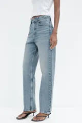 Pantalón de jean negro de tiro alto, corte recto, con cinco bolsillos y cierre frontal con cremallera y botón metálico.
