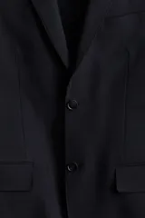 Blazer azul marino de corte slim fit, con solapas de muesca finas, botonadura sencilla con dos botones, bolsillo superior, bolsillos delanteros con solapa, tres bolsillos interiores, botones decorativos en los puños y abertura trasera.