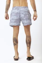 Short de baño con estampado de hojas de palmera en tonos beige, verde y naranja.