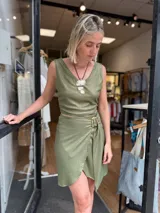 Falda corta cruzada color verde militar con brillo sutil, confeccionada en lino con lurex. Incluye una hebilla decorativa que permite ajustar el calce.