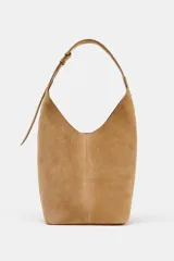 Bolso tipo saca de piel color marrón claro, con asa al hombro y cierre imantado. Incluye cartera interior con cierre de cremallera metálica.