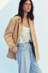 Blazer color camel confeccionada en piel de ante 100%. Diseño clásico con cuello solapa, escote pico, manga larga, bolsillos con solapa en delantero, forro interior combinado, bajo con abertura en espalda y cierre frontal con botones.