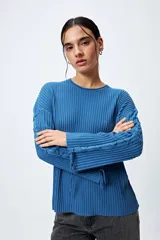 Sweater negro de punto canalé con detalle de trenzado en las mangas y lazo ajustable en el ruedo.