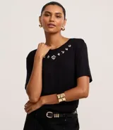 Remera negra de viscosa con cuello redondo y mangas cortas. Presenta apliques de strass en el escote.