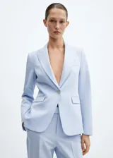 Blazer entallado color beige con cuello de solapa con muesca, manga larga, hombros estructurados, dos bolsillos de ribete en la parte delantera, cierre de botón y abertura posterior.