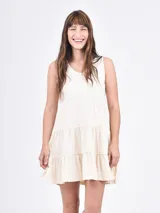 Vestido corto color coral, de corte suelto y sin mangas, con escote en V y falda escalonada con volantes.