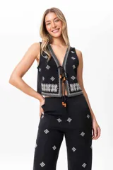 Conjunto de chaleco y pantalón de lino negro con bordado blanco. El chaleco es abierto con tiras ajustables y el pantalón es tipo sastrero con elástico en la parte trasera de la cintura.