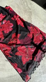 Minivestido de microtul con estampado de flores rojas sobre fondo negro.