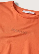 Camiseta de algodón color naranja con logo Mango estampado en el pecho. Diseño recto, cuello redondo y manga corta.