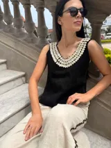 Top negro de cuero con escote en V y apliques de caracoles cosidos a mano en el escote.