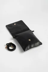 Bandolera negra de cuero sintético con correa larga regulable y cierre con solapa.