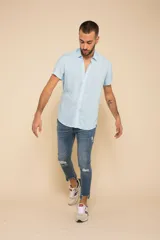 Camisa celeste con estampado floral blanco, de manga corta y corte clásico. Cierre frontal con botones.