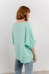 Blusa color beige confeccionada en lino, de corte holgado, mangas 3/4 y cuello redondo.