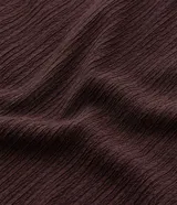 Pantalón de tiro alto, corte flare (acampanado), color marrón oscuro, confeccionado en tejido texturizado anarruga con cintura elástica.