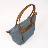 Bolso tipo tote bag color gris azulado con detalles en marrón. Tiene doble asa de hombro marrón, cierre superior y bolsillo frontal con cierre.