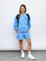 Buzo de felpa azul marino con mangas raglán rojas y detalles tricolor en puños, mangas y cuello. Incluye logo de Umbro bordado en el pecho y escudo del Club Nacional de Football.