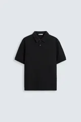 Polo negro de corte regular, con cuello solapa, cierre frontal de botonadura y mangas cortas.
