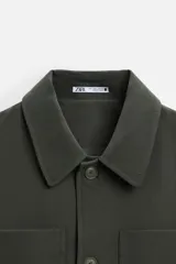 Sobrecamisa verde oscuro de corte cuadrado, con cuello solapa, manga larga con puños abotonados, bolsillos de parche en el pecho y bolsillos laterales en la cadera. Cierre frontal con botones.
