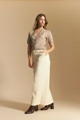 Pantalón largo color crema, tiro alto, de corte recto y ancho. Presenta costuras visibles en contraste y bolsillos delanteros.