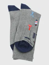 Calcetín de largo medio, color gris jaspeado, con motivos relacionados a la barbería como tijeras, peines, máquinas de afeitar, barber pole y bigotes. El talón y la punta son de color azul marino.