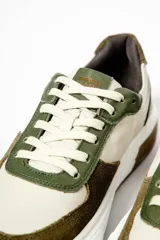 Zapatillas deportivas de cuero color beige, con detalles en verde oliva y marrón.