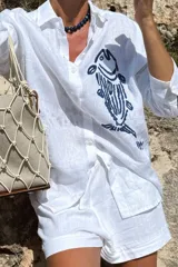 Camisa blanca de lino con bordado de pulpo azul en el pecho, de corte recto y manga larga.