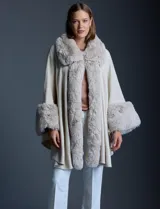 Ruana tejida color crema de la marca Adrienne Vittadini, con cuello, delantera y puños con aplique en símil piel. Delantera con abertura central y botón trenca.