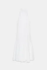Vestido midi blanco, con cuello halter y falda con terminación en godets, lo que le da volumen y movimiento.