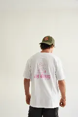 Remera color crema de algodón con estampado en la espalda de un sol, una tabla de surf y el texto "Big Waves Club" en color rosa.