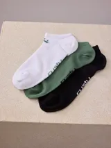 Pack de tres pares de medias de algodón a la altura del tobillo. Un par blanco, un par verde y un par negro. Todos los pares tienen el logo de la marca en el lateral.