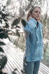 Buzo con capucha de tejido tipo jerga a rayas horizontales en tonos celeste, gris y blanco.