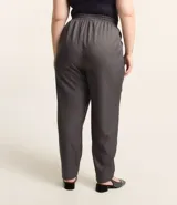 Pantalón de vestir gris oscuro con estampado de raya diplomática, corte recto, cintura alta con elástico en la parte trasera, bolsillos laterales y cierre frontal con botón y cremallera.
