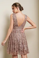 Vestido mini de fiesta color lila con escote en V profundo, sin mangas y falda acampanada. Presenta apliques de lentejuelas doradas formando un diseño floral.