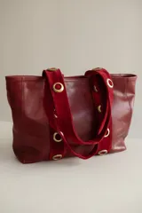 Cartera tote grande de cuero color marrón con asas de cuero con estampado animal print y ojales metálicos dorados.