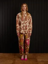 Pantalón de gabardina carrot fit con estampado floral en tonos marrón, naranja y fucsia, con detalles de botones de metal y parche trasero.