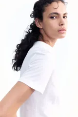 Remera blanca de algodón suave con cuello redondo ribeteado y bajo recto.