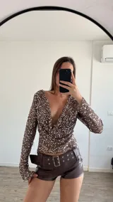 Top de fiesta color blanco, con escote drapeado y lentejuelas.