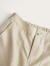 Pantalón cargo color crema, de corte holgado y tiro alto, con bolsillos laterales y detalles de ajuste en los tobillos.