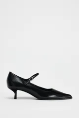 Zapato de cuero negro con tacón kitten, tira delantera con hebilla ajustable y punta fina.
