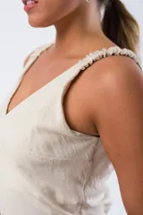 Vestido beige con escote en V y tirantes fruncidos.