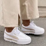 Championes Puma Mayze blancos con franja lateral negra y suela de plataforma con detalles en negro.