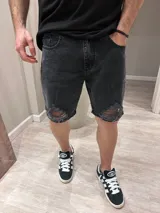 Bermuda de jeans gris oscura, con roturas y desgaste en la parte frontal.