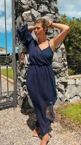 Vestido largo azul marino con un hombro descubierto, manga larga abullonada y falda irregular con sobrevestido de crepé.