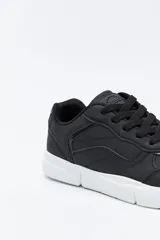 Zapatilla urbana blanca de mujer, con silueta moderna y líneas limpias. Presenta detalles en poliuretano liso y un panel plateado en el talón. La suela es de perfil recto y firme.