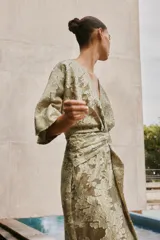 Vestido midi color verde oliva con estampado floral, escote en V, manga corta amplia y detalle drapeado en la cintura.
