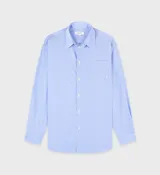 Camisa celeste con rayas verticales blancas, de corte amplio y manga larga.