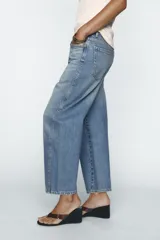 Pantalón de jean celeste de corte amplio, con tiro medio, cinco bolsillos y costuras torcidas.
