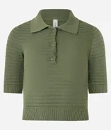 Blusa de punto color crema, con cuello polo, mangas cortas y puños con botones.